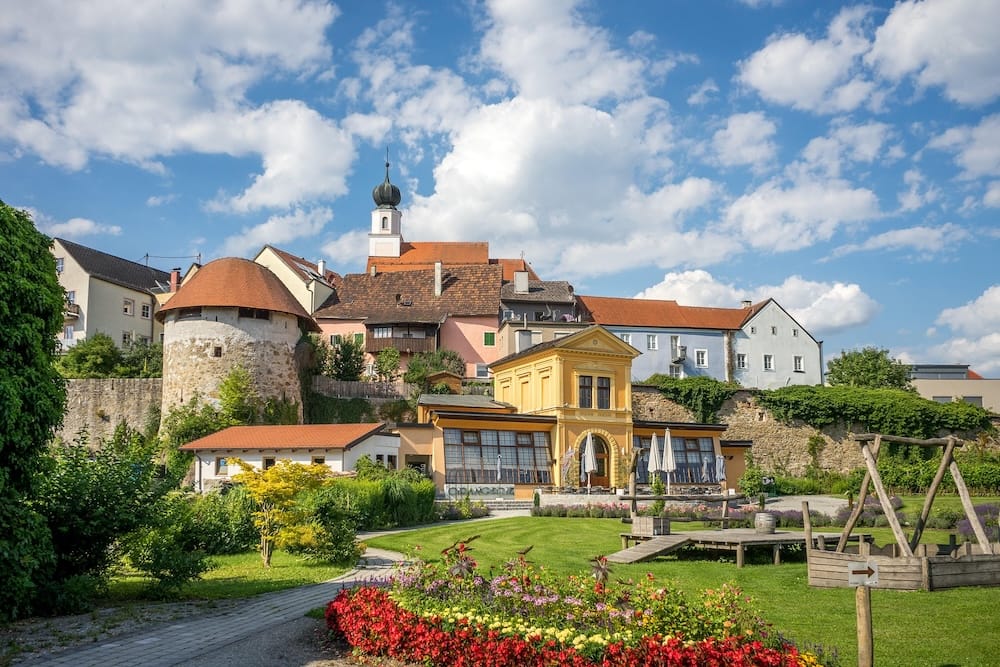 chaerding-baroque-town-upper-austria Brightly colored historic houses, an old stone fortifications tower, and a church steeple in the Baroque town of Schärding, Upper Austria